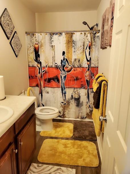 full bath featuring toilet, a shower with curtain, wood finished floors, and vanity