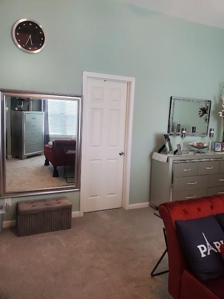 bedroom featuring carpet floors, baseboards, and a towering ceiling