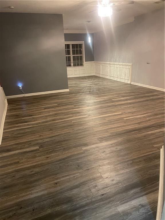 2118 Burns View Ln, Lawrenceville, GA 30044 - empty room with ceiling fan, dark wood-style flooring, a wainscoted wall, and baseboards