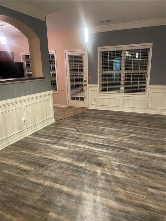 2118 Burns View Ln, Lawrenceville, GA 30044 - empty room featuring crown molding, dark wood-style flooring, a decorative wall, wainscoting, and arched walkways