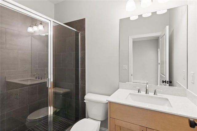 bathroom with toilet, vanity, and a shower with shower door