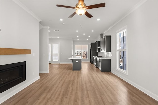 kitchen featuring crown molding, a breakfast bar, and a center island with sink