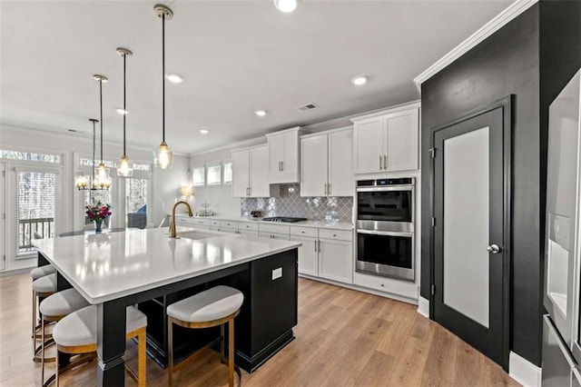 kitchen featuring ornamental molding, double oven, black gas stovetop, and a sink