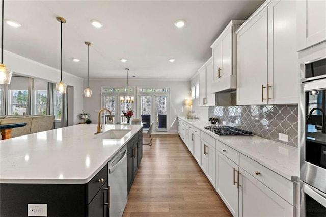 kitchen with backsplash, under cabinet range hood, ornamental molding, appliances with stainless steel finishes, and a sink