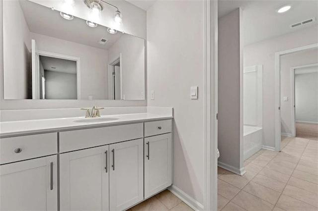 bathroom featuring vanity, visible vents, baseboards, a tub, and tile patterned flooring