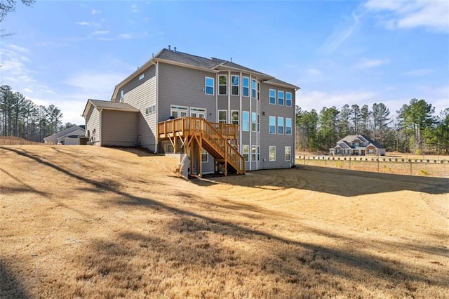 back of property with a yard, a deck, and stairs