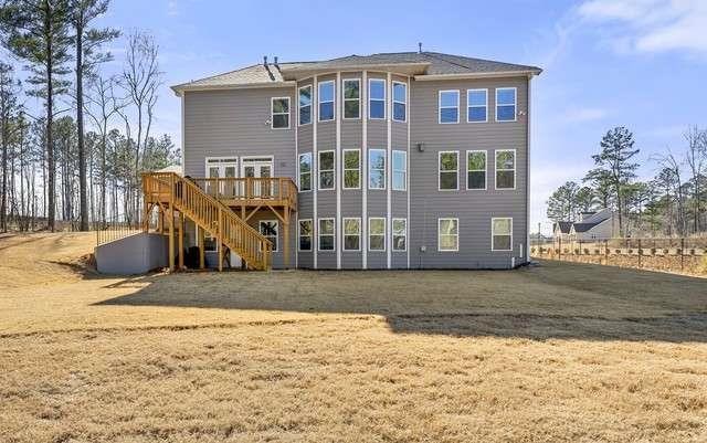 rear view of house featuring stairway, a lawn, and a wooden deck