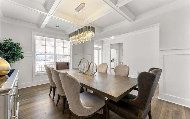 dining area featuring coffered ceiling, dark wood finished floors, beam ceiling, an inviting chandelier, and a decorative wall