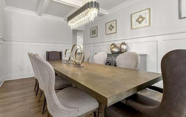 dining area featuring crown molding, beam ceiling, an inviting chandelier, wood finished floors, and a decorative wall