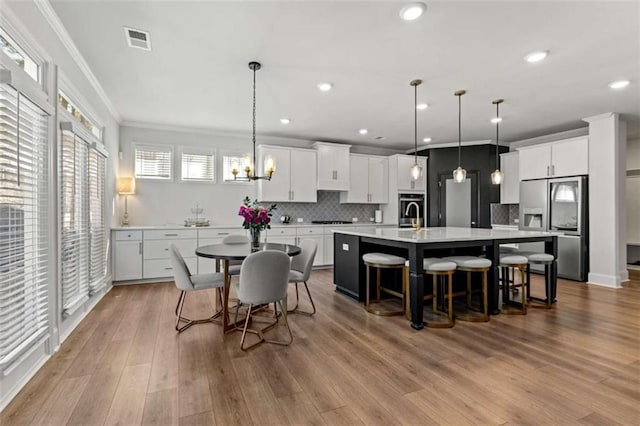 dining area with wood finished floors, visible vents, recessed lighting, ornamental molding, and a notable chandelier