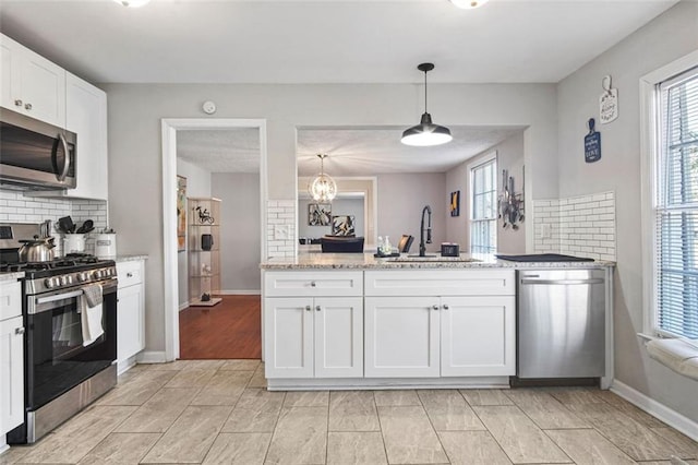 kitchen with pendant lighting, sink, white cabinets, tasteful backsplash, and stainless steel appliances