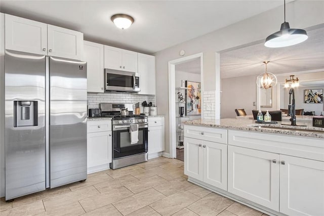 kitchen featuring decorative light fixtures, sink, white cabinets, and appliances with stainless steel finishes