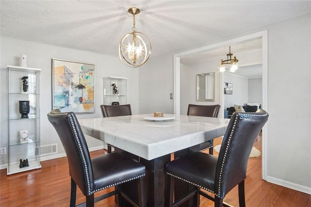 dining area featuring a chandelier, a textured ceiling, and dark hardwood / wood-style flooring