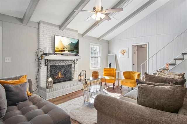 living room featuring wood-type flooring, vaulted ceiling with beams, a fireplace, wood walls, and ceiling fan