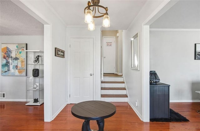 corridor featuring wood-type flooring, crown molding, and a notable chandelier