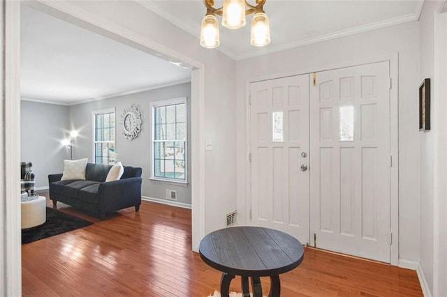 foyer with a notable chandelier, hardwood / wood-style floors, and crown molding