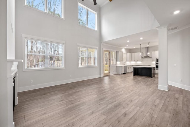 3390 Hillshire Dr, Cumming, GA 30028 - unfurnished living room featuring light wood-type flooring, a towering ceiling, ceiling fan, baseboards, and ornamental molding
