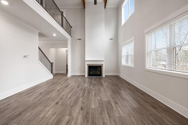 3390 Hillshire Dr, Cumming, GA 30028 - unfurnished living room featuring a towering ceiling, stairs, wood finished floors, baseboards, and a fireplace
