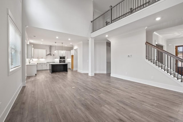 3390 Hillshire Dr, Cumming, GA 30028 - unfurnished living room with a towering ceiling, wood finished floors, baseboards, a sink, and stairs