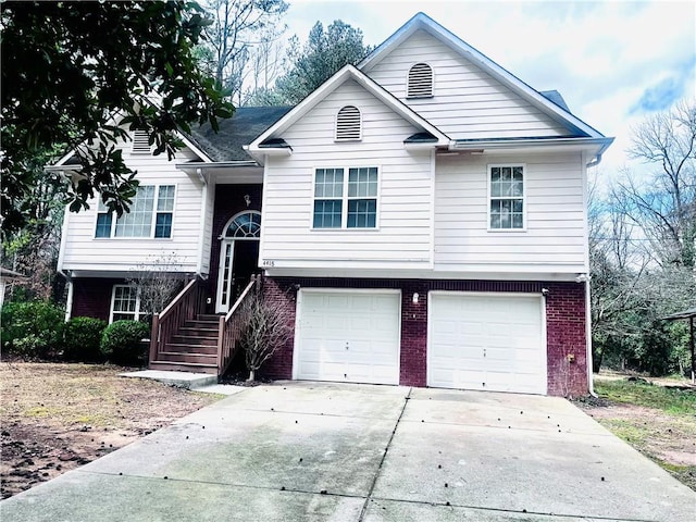 raised ranch with concrete driveway, brick siding, and an attached garage