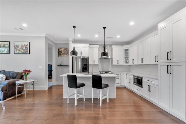 6890 Peachtree Dunwoody Rd Unit 303, Atlanta, GA 30328 - kitchen with appliances with stainless steel finishes, wall chimney exhaust hood, a kitchen island, ornamental molding, and a breakfast bar