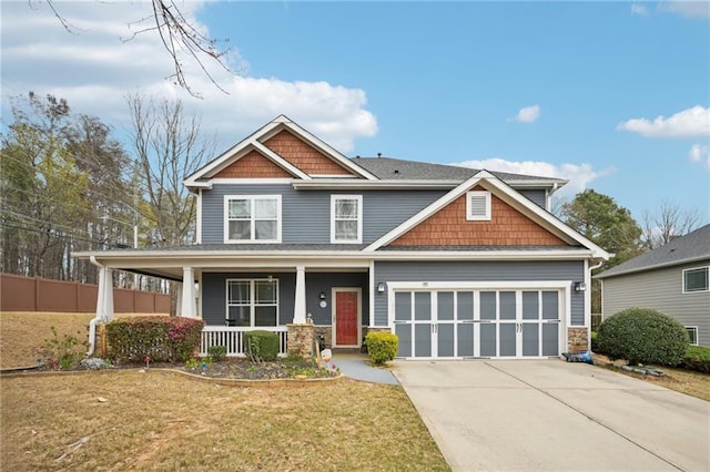 craftsman-style home featuring fence, an attached garage, a front lawn, driveway, and covered porch