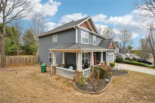 view of home's exterior with fence, concrete driveway, and a porch