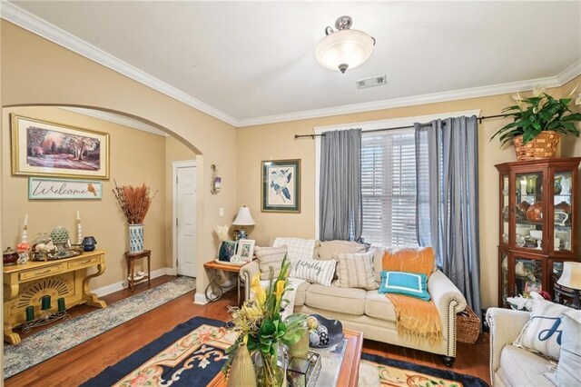 living room featuring ornamental molding, baseboards, arched walkways, visible vents, and wood finished floors
