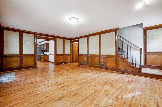 unfurnished living room with wooden walls and light hardwood / wood-style flooring