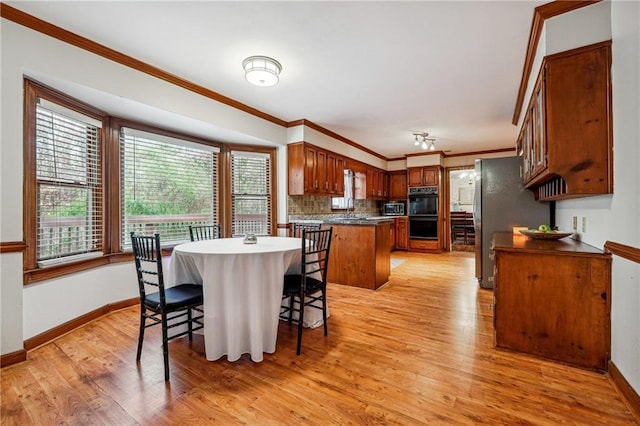 dining space with light hardwood / wood-style floors, ornamental molding, and sink