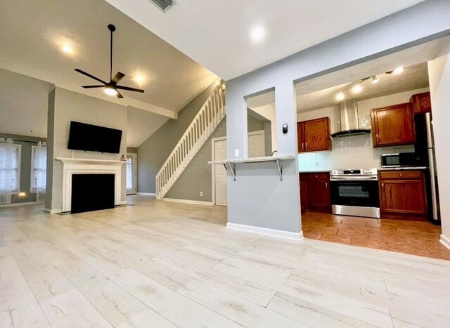 kitchen featuring wall chimney exhaust hood, sink, light stone counters, stainless steel appliances, and backsplash