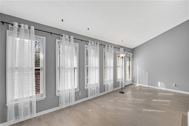 unfurnished room with ceiling fan, vaulted ceiling, and light wood-type flooring