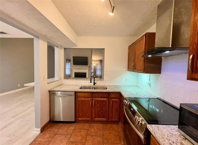 kitchen with visible vents, wall chimney exhaust hood, appliances with stainless steel finishes, open floor plan, and a sink