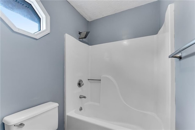 bathroom with toilet, bathtub / shower combination, and a textured ceiling