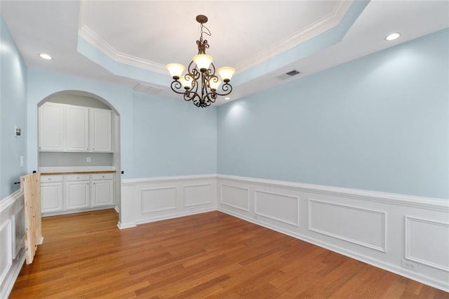 3362 Palm Cir NW, Kennesaw, GA 30144 - unfurnished dining area with a chandelier, a raised ceiling, ornamental molding, a wainscoted wall, and light wood finished floors