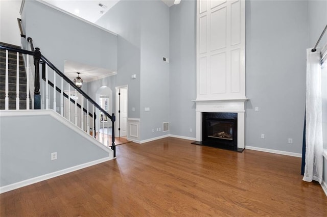 3362 Palm Cir NW, Kennesaw, GA 30144 - unfurnished living room featuring a towering ceiling, stairway, wood finished floors, a fireplace, and arched walkways