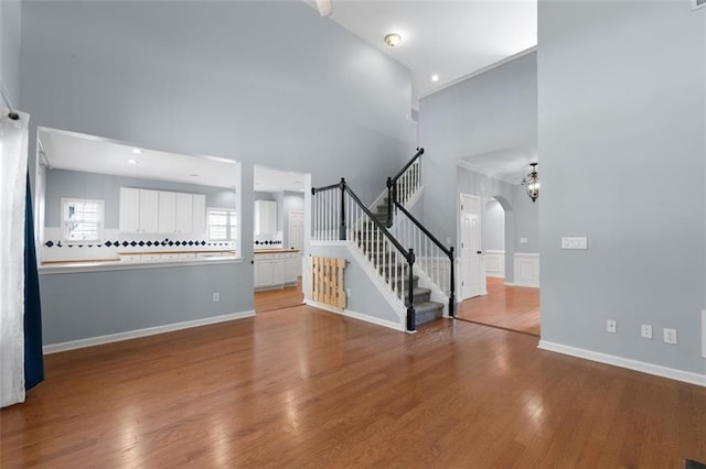 3362 Palm Cir NW, Kennesaw, GA 30144 - unfurnished living room featuring a towering ceiling, arched walkways, wood finished floors, stairway, and baseboards