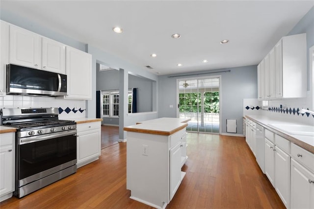 3362 Palm Cir NW, Kennesaw, GA 30144 - kitchen featuring appliances with stainless steel finishes, wood finished floors, backsplash, a center island, and white cabinets