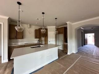 5444 Miravista Way, Hoschton, GA 30548 - kitchen featuring arched walkways, a kitchen island with sink, light countertops, decorative light fixtures, and crown molding