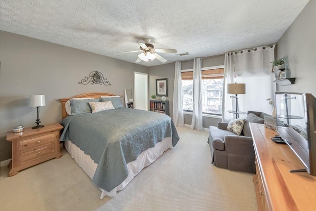 bedroom with visible vents, light colored carpet, a textured ceiling, and ceiling fan