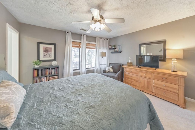 carpeted bedroom featuring a ceiling fan, visible vents, and a textured ceiling