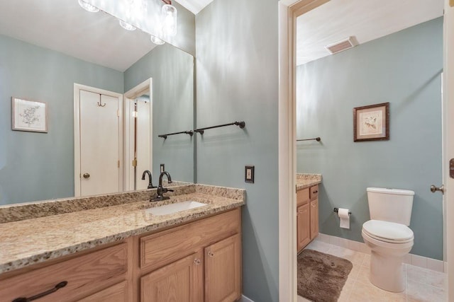 bathroom featuring vanity, baseboards, visible vents, tile patterned floors, and toilet