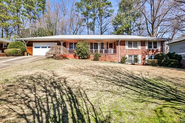 view of front of home with covered porch, concrete driveway, brick siding, and an attached garage