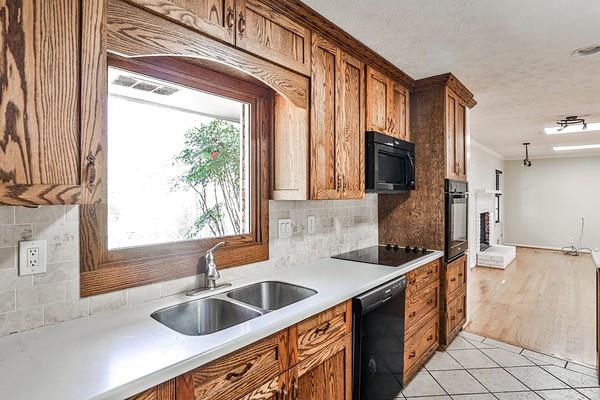 kitchen with light tile patterned floors, black appliances, a sink, and a healthy amount of sunlight