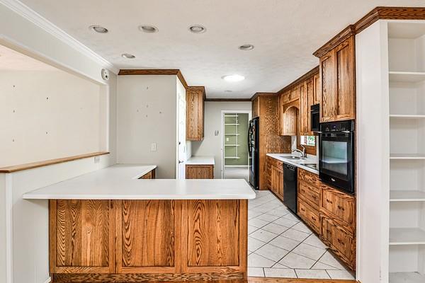 kitchen with crown molding, light countertops, a sink, and black appliances