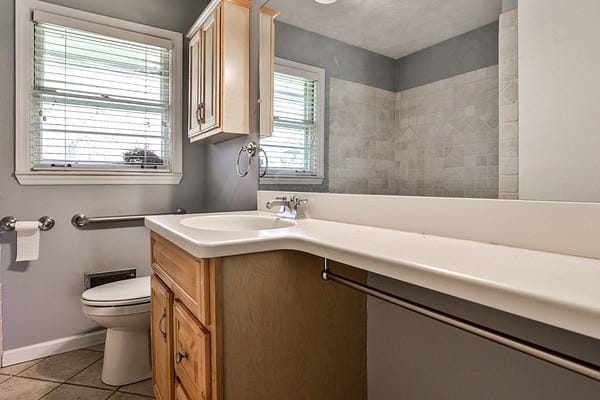 bathroom featuring toilet, tile patterned flooring, vanity, and baseboards