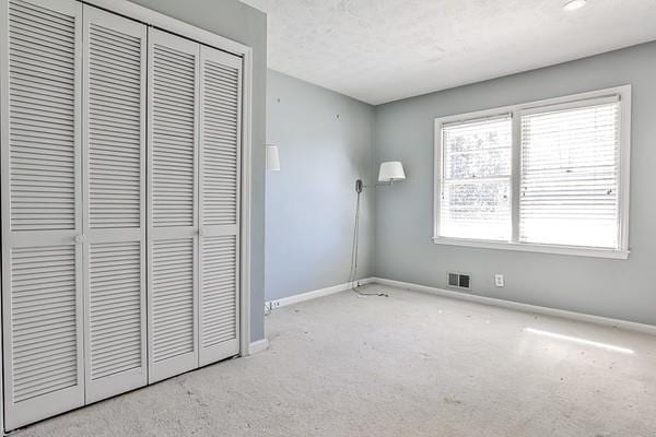 unfurnished bedroom with a closet, visible vents, and baseboards