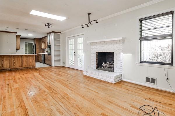 unfurnished living room with light wood finished floors, french doors, visible vents, and crown molding