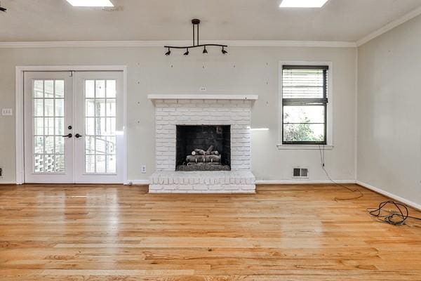 unfurnished living room with visible vents, wood finished floors, crown molding, and french doors