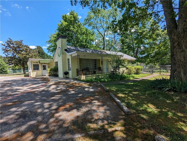 exterior space with covered porch, a chimney, and fence